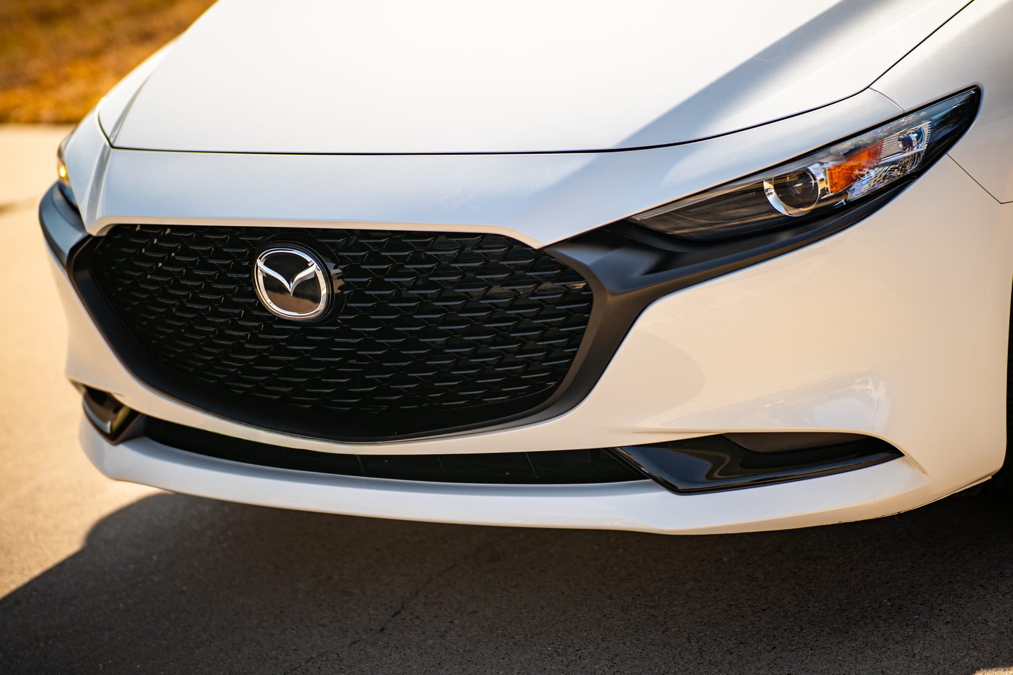 Mazda 3 front end after a chrome delete, with the grille trim wrapped in gloss black